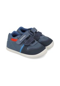 Zapatillas azul y marino con correas de velcro, suela de goma y acentos en rojo y azul. Material superior suave con detalles de costura.