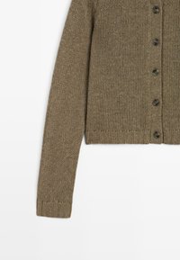 Bruine gebreide cardigan met een geribde zoom, lange mouwen en zes donkere knopen aan de voorkant. De textuur lijkt dik en textuurvol te zijn.