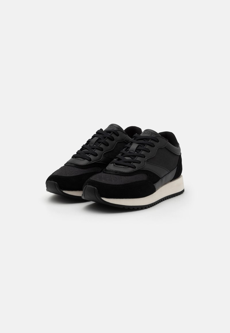 Zapatillas negras con un upper de materiales mixtos, que combina cuero liso y ante. Presenta una suela exterior negra texturizada y una entresuela de color claro.