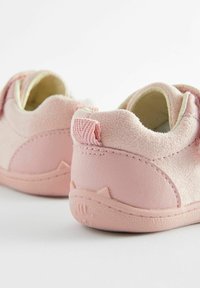 Chaussures pour tout-petits roses en suède et cuir doux. Forme arrondie, finition texturée, et petites oreilles de chat accentuées sur le talon.