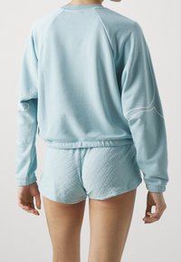 Světlomodrý sweatshirt s ribbed manžetami a spodním lemem, doplněný o ladící texturované šortky s diamantovým vzorem.