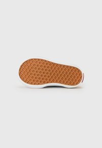 Semelle de sneaker en caoutchouc avec un motif texturé en nid d'abeille de couleur gomme et une bordure blanche. Accent rouge au talon.