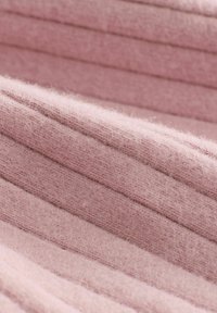 Struktureret, ribbet stof i blød lyserød, der har fine, fuzzy fibre og lodrette striber. Materialet fremstår varmt og hyggeligt.