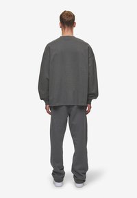 Gray oversized sweatshirt with a crew neck, paired with matching gray sweatpants, both made of soft fabric. Minimalistic design with no visible patterns.