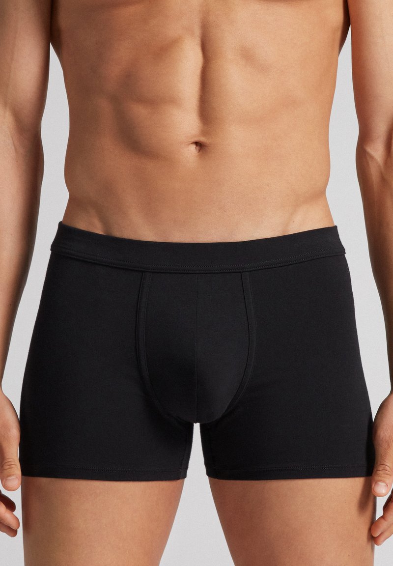 Boxer shorts en coton noir avec une texture lisse. Dotés d'une large ceinture et d'un design de poche de soutien. Coupe ajustée pour le confort.