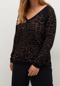 Czarny sweter z długim rękawem w brązowy wzór w panterkę, z dekoltem w kształcie V i prążkowanymi mankietami. Tkanina wydaje się być strukturalna.