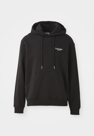 Schwarzer Kapuzenpullover mit langen Ärmeln, großer vorderer Tasche und weißem "Calvin Klein Jeans"-Logo auf der oberen linken Seite. Stoff aus Baumwollmischung.