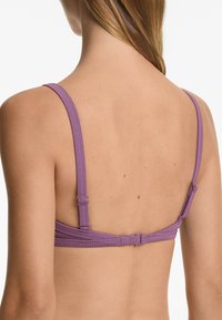 Lila ribbad bralette med justerbara axelband och en krokuppsättning bak. Slät textur och minimaliskt design.