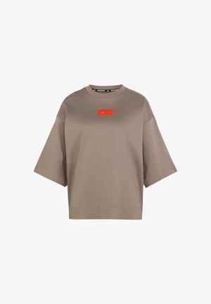 Bruine oversized t-shirt van zacht katoen, met een ronde hals en korte mouwen. Opvallende rode logoafbeelding op de voorkant.