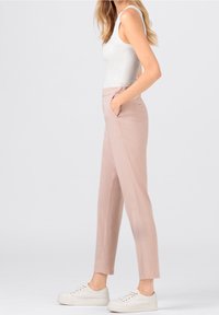 Pink cotton trousers with side pockets, tapered shape, and elastic waistband, paired with a white ribbed tank top and white sneakers.