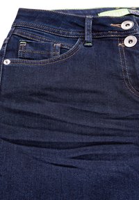 Jean en denim bleu foncé avec une texture lisse, comportant cinq poches, deux boutons à l'avant et des coutures contrastantes le long des coutures.