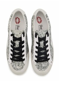 Baskets scintillantes argentées et blanches avec un dessus texturé, des lacets noirs et des semelles en caoutchouc. L'intérieur présente un logo avec des lèvres rouges.