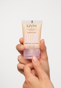 Fond de teint NYX Bare With Me Blur dans un tube beige avec une base rose. Dispose d'un distributeur à pompe ; étiqueté "04 : Neutre Clair." Taille de 30 mL.