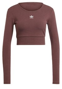 Brun ribbad crop-top med långa ärmar; har en rund halsringning och vit Adidas-logotyp på bröstet. Mjukt, stretchigt material.