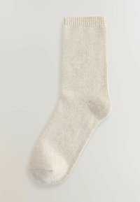 Cream-colored cotton sock with ribbed top, seamless toe closure, and a soft texture. Straight shape with no patterns or embellishments.