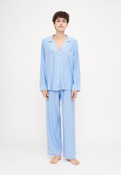 Ensemble de pyjama rayé bleu clair en tissu doux. Haut à manches longues avec boutons et poche poitrine, associé à un pantalon à jambes larges.