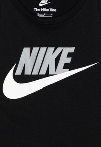 Juodas medvilnės marškinėliai su dideliu baltu "NIKE" tekstu ir baltu swoosh logotipu. Apvalus iškirptės dizainas ir švelni tekstūra, tinkama kasdieniam dėvėjimui.