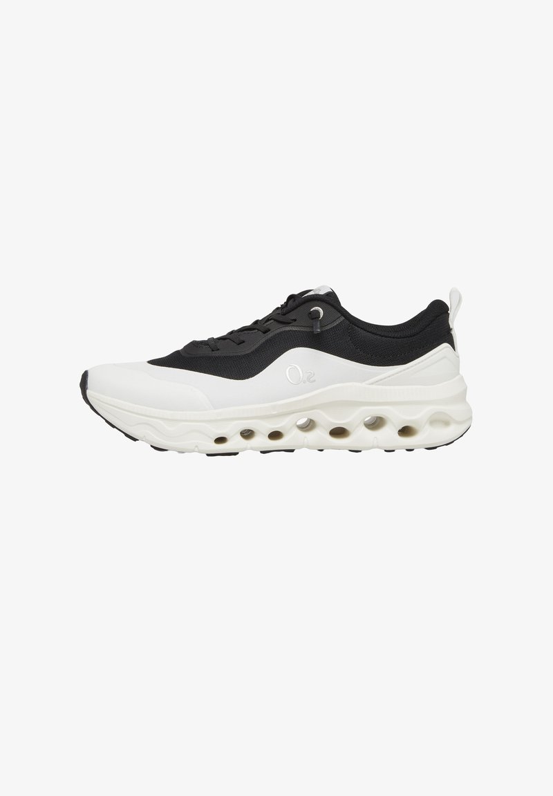 Czarno-biały sportowy sneaker z zapięciem na sznurówki, oddychającą siateczkową cholewką oraz grubą białą podeszwą z okrągłymi wycięciami.