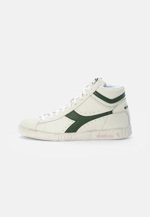 High-top sneakers in white leather with green accents. Features perforated detailing, white laces, and a textured rubber sole.