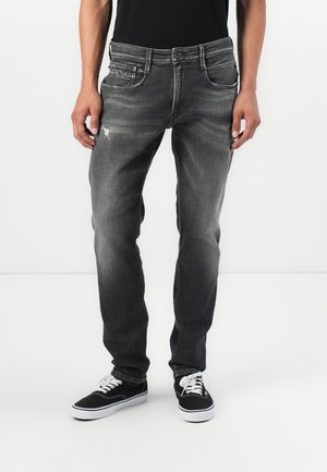 Havede sorte denim jeans med lige snit, der har et slidt mønster og forlommer. Båret med sorte sneakers.