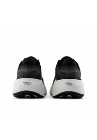 Svarta sportskor med en texturerad överdel och vit vadderad sula, som har texten "FRESH FOAM" på hälen och logotypdetaljer.