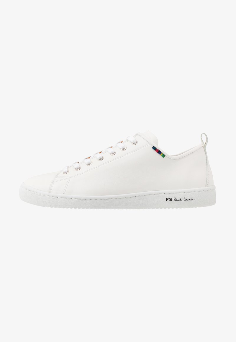 Zapatilla de cuero blanca con textura suave, puntera redonda y detalle de tira de color contrastante cerca de los cordones. Presenta una suela de goma y un logotipo en el lateral.
