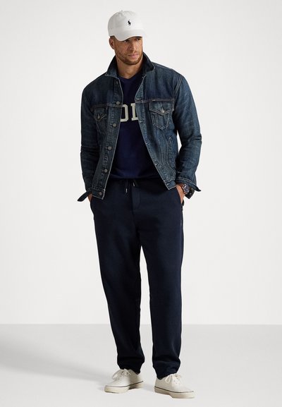 Jachetă din denim, hanorac bleumarin cu inscriptionarea "POLO", pantaloni de trening bleumarin, adidași albi și șapcă albă cu logo. Îmbrăcăminte lejeră, stratificată.