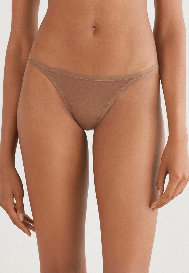Bruine katoenen stringonderbroek met een laag uitgesneden ontwerp en dunne zijkanten, met een gladde textuur en minimale stiksel-details.