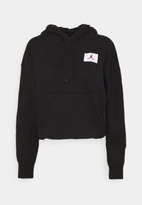 Sudadera recortada negra de tela suave. Presenta un bolsillo frontal, capucha con cordón y un parche blanco contrastante con un logo.