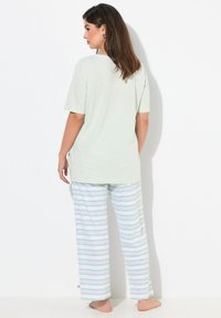 Ljusgrön kortärmad topp kombinerad med randiga pyjamasbyxor i vitt, grönt och lavendel. Mjuk tyg, avslappnad passform och ankellängd.