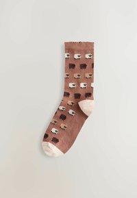 Bruine sok met een patroon van kleurrijke schapen in verschillende tinten, tegen een lichte achtergrond.