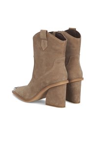 Botas de tobillo de ante marrón con punta cuadrada, detalles metálicos plateados y un sólido tacón cuadrado. Incluyen una cremallera lateral y tiradores.