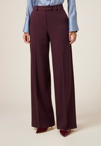 Bordeaux wijde broek met een gladde afwerking, voorzien van een gestructureerde tailleband, riemlussen en scherpe plooien voor extra detail.