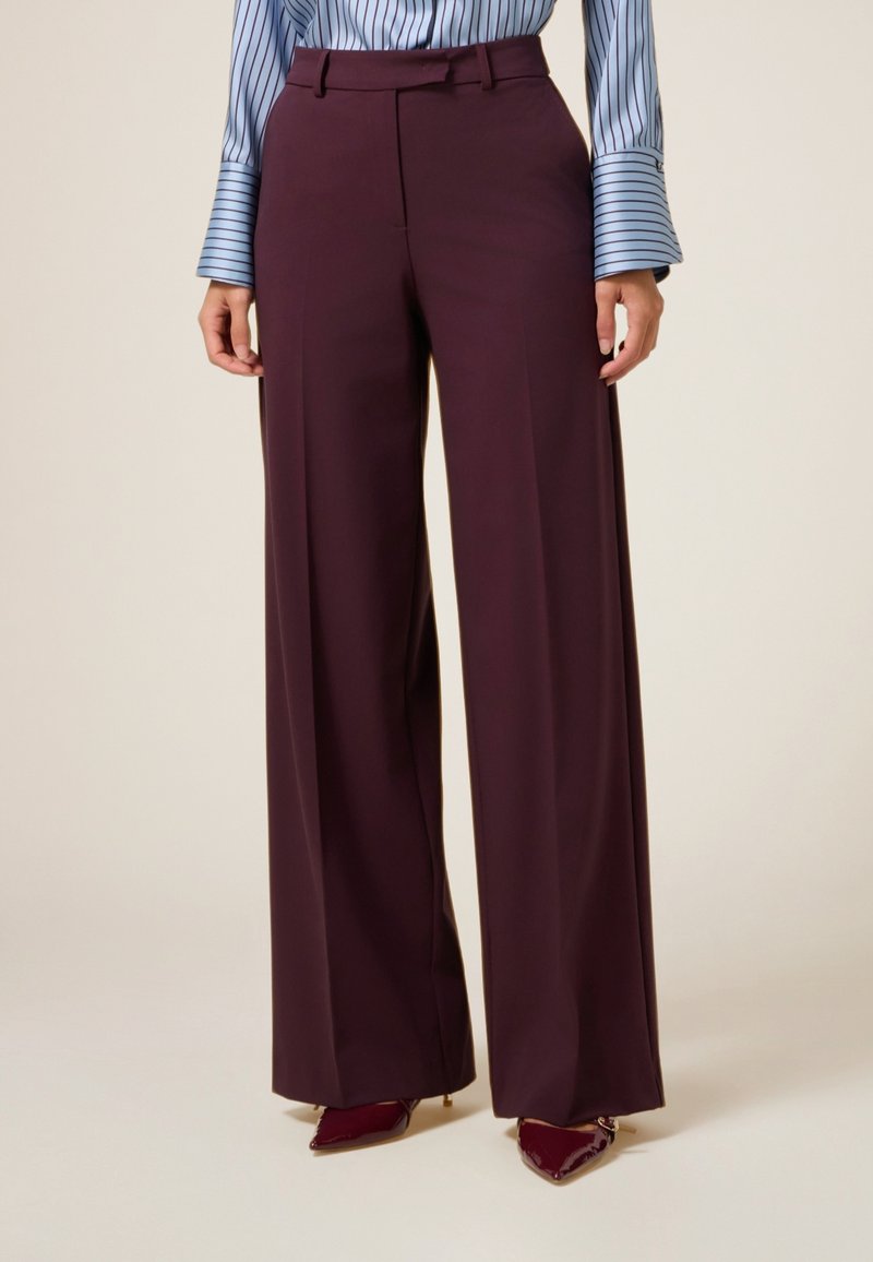Bordeaux wijde broek met een gladde afwerking, voorzien van een gestructureerde tailleband, riemlussen en scherpe plooien voor extra detail.