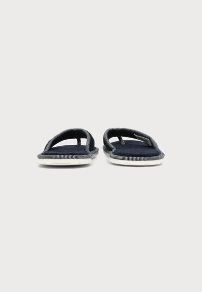 Paire de chaussons bleu foncé à bouts ouverts avec semelles blanches, vues de face sur un fond clair uni.