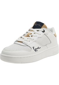 Zapatilla blanca con detalles de cuero perforado y malla, cordones beige y talón en azul marino. Presenta un logo distintivo en el lateral. Suela de goma plana.