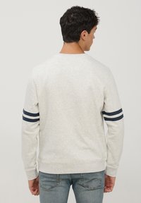 Szary heatherowy sweatshirt z granatowymi paskami na rękawach, z okrągłym dekoltem i ściągaczami na rękawach. Miękka, podobna do tkaniny polarowej tekstura.