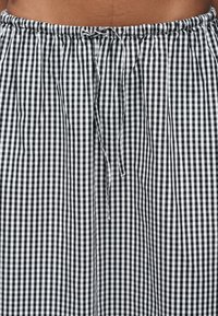 Ύφασμα με ασπρόμαυρο καρό μοτίβο gingham, με ελαστική μέση και κορδόνι δεμένο σε φιόγκο στο κέντρο.