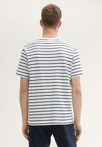 T-shirt à manches courtes rayé blanc et marin, en coton doux, avec un col rond et une coupe droite. Pas de logos ni de graphismes visibles.