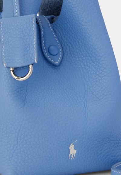Υφασμένο δερμάτινο τσαντάκι σε ανοιχτό μπλε χρώμα με ασημί μεταλλικό δαχτυλίδι, ραμμένο λουράκι με κουμπί πατιλέτα και μικρό λογότυπο λευκού παίκτη πόλο αλόγου.