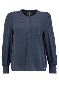 Laivastonsininen paita, jossa on pieniä valkoisia pilkkuja, pyöreä pääntie, napitettu yksityiskohta, pitkät liehulahkeiset hihat ja kerätyt hihansuut. Pehmeä kangas.