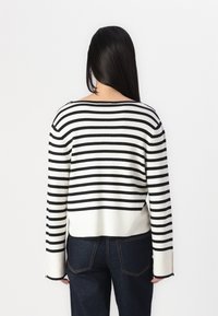 Black and white striped sweater with a wide neckline and long sleeves, paired with dark denim jeans. Soft knit fabric.