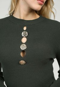Pull côtelé vert foncé doté de trois boutons ronds décoratifs aux motifs détaillés, avec un col arrondi et des ouvertures en forme de goutte d'eau.
