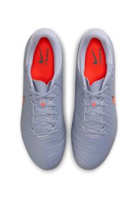 Chaussures de soccer grises avec une tige texturée, présentant un intérieur orange vif et un logo Nike noir. Six paires de lacets gris.
