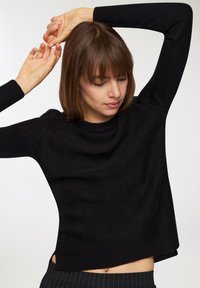 Pullover nero in maglia con scollatura rotonda, maniche lunghe e vestibilità rilassata. Presenta polsini e orlo a coste, che mettono in risalto un tessuto testurizzato.