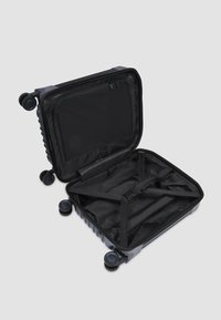 Hartschalenkoffer in Dunkelgrau mit offenem Reißverschluss. Innenraum mit schwarzer Stoffauskleidung, Kreuzriemen und einer Reißverschlusstasche. Vier Rollen.