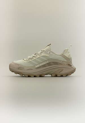 Jasnobeżowy but trekkingowy Merrell z wytrzymałą podeszwą, siateczkową cholewką, sznurówkami i pętlami na pięcie i języku na neutralnym tle.