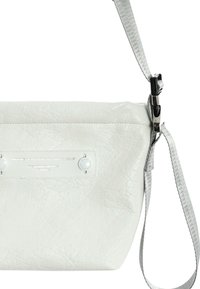 Bolso cruzado de cuero blanco con superficie texturizada, con una correa plateada, cierre de broche y una etiqueta con el logo en el frente.