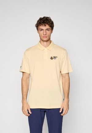 Gul polo skjorte med krage, med broderte design på brystet. Korte ermer og myk stoff. Brukes med marineblå bukser.
