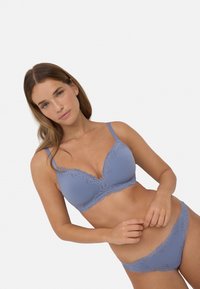 Sujetador azul claro con encaje en los bordes y diseño de escote en V, acompañado de panties a juego con bordes de encaje. Tejido texturizado.